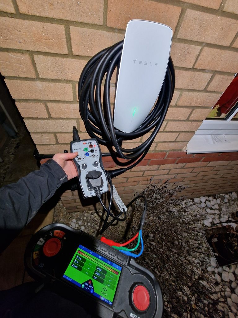 Tesla EV charger installed on an external brick wall in Bradley Stoke, Bristol, with electrical testing equipment connected